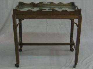 A Chippendale style mahogany tray raised on a trolley 26"