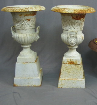A pair of Victorian style cast iron urns of twin handled campanular form raised on square bases 19"
