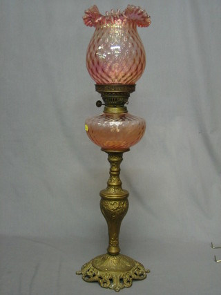 A Victorian oil lamp with red glass reservoir and shade