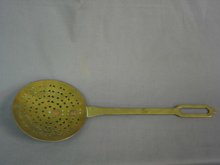 A circular brass cream skimmer