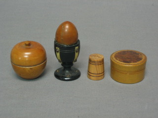 A circular treen box in the form of an apple 2", a circular cylindrical jar and cover 2", a thimble and a Victorian treen novelty in the form of an egg and cup
