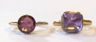 A gold dress ring set a cabouchon cut garnet coloured stone and 1 other gold dress ring set an amethyst coloured stone