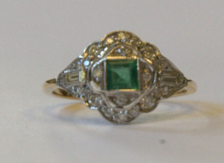 A lady's 18ct yellow gold dress ring set a square cut emerald supported by numerous diamonds