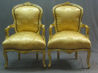 A pair of 20th Century gilt painted open arm salon chairs