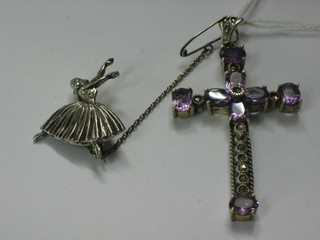 A silver brooch in the form of a ballerina and a cross set amethyst coloured stones