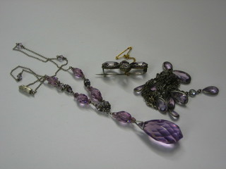 An amethyst coloured tear drop pendant, a string of amethyst coloured beads and an amethyst brooch