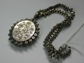 A Victorian oval silver engraved locket hung on a silver chain