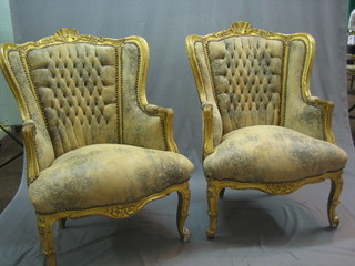 A pair of French style gilt painted wing back armchairs upholstered in weathered leather