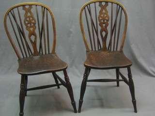 A pair of 19th Century stick and elm wheel back dining chairs with solid seats, raised on turned supports