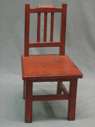 A childs  Eastern red painted stick and rail back chair