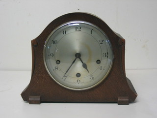 A 1930's striking mantel clock with silvered dial and Arabic numerals contained in an oak arch shaped case