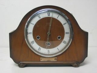 A striking mantel clock with silvered dial and Roman numerals contained in an arched walnut case