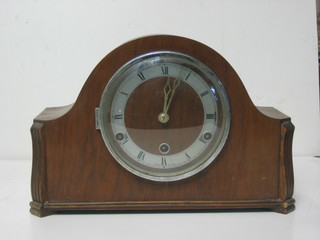 A striking mantel clock with silvered dial and Roman numerals contained in an arch shaped walnut case
