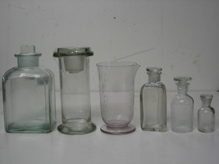 A  square chemists glass bottle 6", a triangular shaped do. 4" and 2 others, a ginger jar and cover and a glass measuring jug