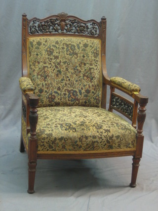A Victorian heavily carved walnut open arm chair on turned and reeded supports