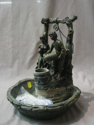 A bronzed water feature in the form of a boy and girl stood by a well head 12"