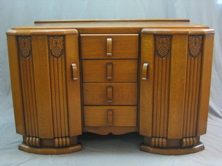 A 1930's Art Deco honey oak sideboard, fitted 4 long drawers, flanked by a pair of cupboards 52"