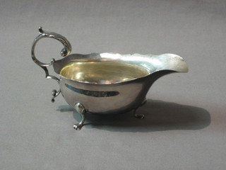 A Georgian style silver sauce boat with cut border and C scroll handle, raised on hoof feet, London 1961 by Mappin & Webb, 4 ozs