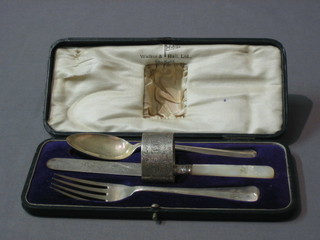A matched silver 4 piece christening set comprising knife, fork spoon and napkin ring, knife Sheffield 1910, fork and spoon Sheffield 1920, napkin ring Chester 1906, all by Walker & Hall, cased