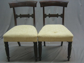 A pair of Victorian mahogany bar back dining chairs with carved mid rails and upholstered seats, raised on turned and reeded supports
