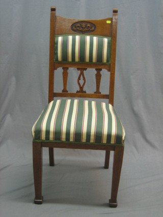 An Edwardian carved oak Art Nouveau stick and bar back chair, raised on square tapering supports