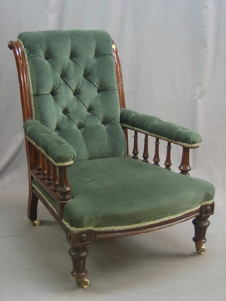 A Victorian oak armchair with bobbin turned decoration, the seat and back upholstered in green buttoned material, raised on turned supports