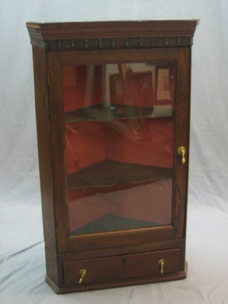 An 18th/19th Century oak hanging corner cabinet with moulded cornice, the interior fitted shelves enclosed by a glazed panelled door, the base fitted 1 long drawer 25"