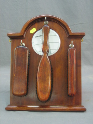 A hanging clothes brush set with 3 brushes in a mahogany frame