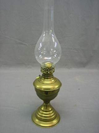 A brass oil lamp with clear glass chimney