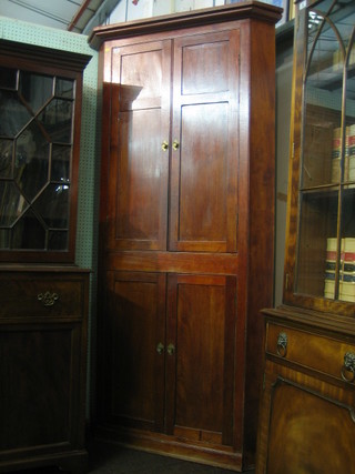 A 19th Century mahogany double corner cabinet with moulded cornice, the interior fitted shelves enclosed by panelled doors raised on a platform base 44"