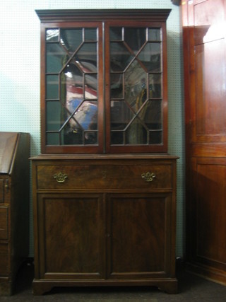 A Georgian style mahogany bookcase on cabinet the upper section with moulded and dentil cornice, the shelved interior enclosed by astragal glazed doors, the base fitted 1 long drawer above a cupboard, raised on bracket feet 37"