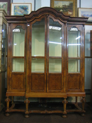 An Italian style walnut break front cabinet on stand with an arch shaped top, fitted adjustable shelves enclosed by glazed panelled doors 65"