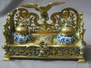 A handsome 19th Century pierced brass inkwell surmounted by a figure of an eagle with wings outstretched, fitted a stamp box to the middle (hinge f) and having 2 blue porcelain inkwells
