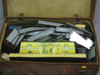 An old leather suitcase containing a Triang tin plate station and various items of track etc