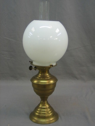 A brass oil lamp with opaque glass chimney and clear glass shade