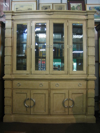 A handsome 20th Century limed oak display cabinet of architectural form, the upper section fitted shelves enclosed by glazed panelled doors, the base fitted 2 drawers above a double cupboard, raised on a platform base 71"