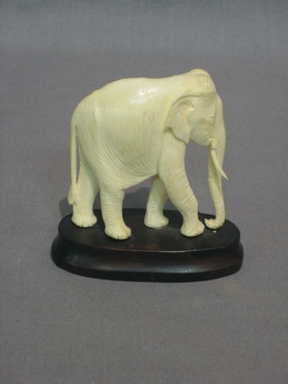 A painted carved ivory figure of a walking elephant 8"
