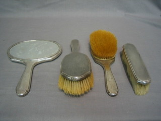 A 4 piece silver backed dressing table set comprising handmirror, clothes brush and a pair of hair brushes, Birmingham 1928