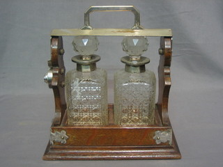 A silver plated and oak 2 bottle tantalus with 2 cut glass spirit decanters