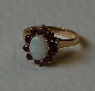A lady's 9ct gold dress ring set an oval cut opal surrounded by rubies