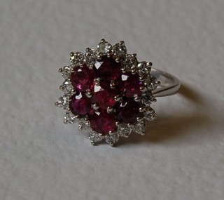 A lady's 18ct white gold cluster ring set 7 rubies surrounded by numerous diamonds