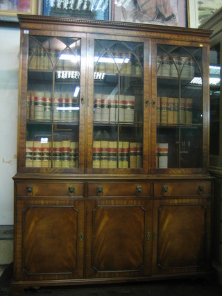 A Georgian style mahogany bookcase on cabinet, the upper section with moulded and dentil cornice, the interior fitted adjustable shelves enclosed by astragal glazed panelled doors, the base fitted 3 long drawers above a triple cupboard, raised on bracket feet 60"