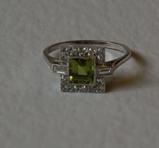 A lady's 18ct white gold dress ring set a square cut peridot surrounded by diamonds and with 2 baguette cut diamonds to the shoulders