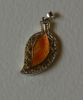 A gold and enamelled leaf shaped pendant set diamonds