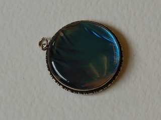 A circular silver and butterfly pendant