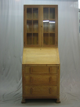 A 1930's Heales style limed oak bureau bookcase, the upper section fitted shelves enclosed by an astragal glazed panelled door, the fall front revealing a well fitted interior above 3 long drawers 27"