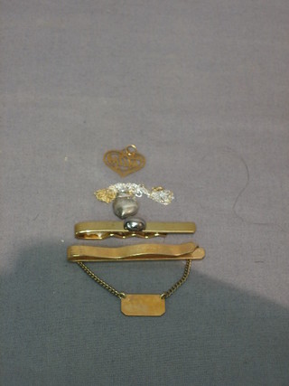 2 gilt metal tie clips, a gold pendant and a fine gold chain hung a heart shaped pendant