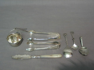 2 pairs of silver sugar tongs, a childs small silver spoon, a silver handled butter knife, a tea strainer and other flatware