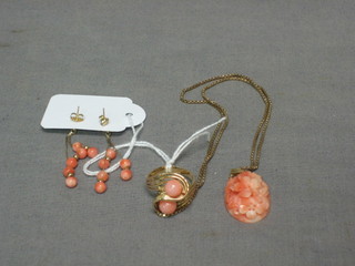 A suite of gold and coral jewellery comprising a gold ring set 2 coral, a coral pendant hung on a gold chain and a pair of earrings