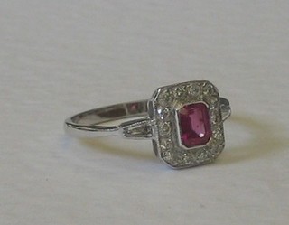 A lady's 18ct white gold dress ring set a square cut ruby surrounded by numerous diamonds having 2 baguette cut diamonds to the shoulders, approx 0.40/1.80ct